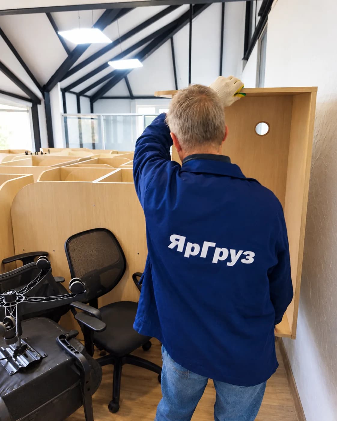Грузчик переносит офисную мебель во время переезда